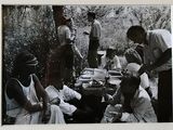 une photo en noir et blanc montrant un groupe de personnes assises autour d'une table