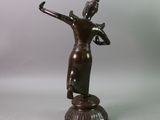 bronze statue of a woman holding a bird on a pedestal