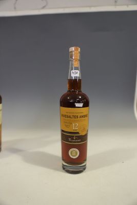 two bottles of whiskey sit on a counter in front of a computer