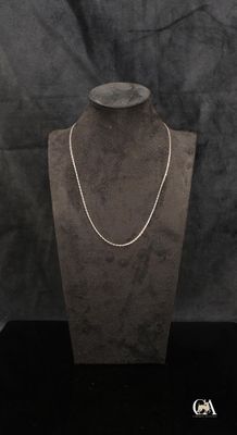 un collier posé sur un présentoir pour mannequin, sur fond noir
