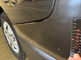 a person holding a ruler in front of a car