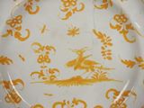 a yellow plate with a bird and flowers on it