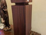 une statue représentant un homme assis sur une table, à côté d'un vase