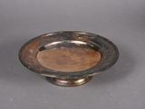 an antique silver plate on a gray surface