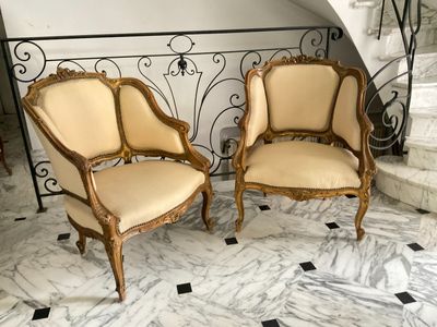 pair of antique french style chairs on marble flooring in front of a spiral staircase