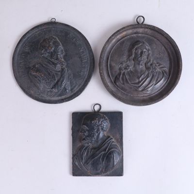 trois médaillons en bronze représentant un homme et une femme sur fond blanc