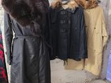 un manteau sur un mannequin devant un portemanteau rempli de manteaux