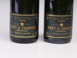two bottles of champagne sitting next to each other on a white surface