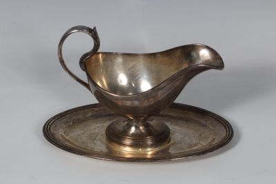 a silver gravy on a silver plate on a table