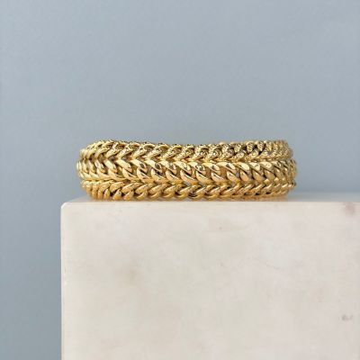 un gros plan d'un bracelet en or posé sur un bloc de marbre
