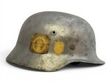 an old silver helmet with a yellow patch on the side of it