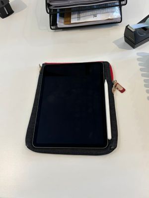a tablet on a desk with a pen and a cell phone