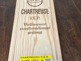 La boîte en bois est posée sur la table, avec son étiquette dessus.