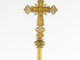a gold cross on a black pole with a white background