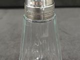 une image représentant une salière en verre avec un couvercle argenté