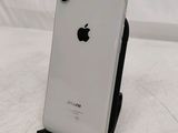 a white iphone sitting on a stand on a bed