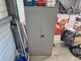 a metal cabinet in a garage with a red fire hydrant