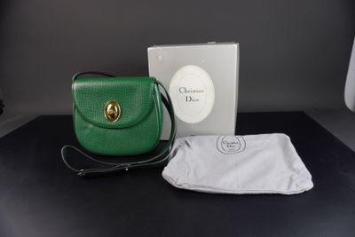 Le petit sac à main vert se trouve à côté d'une boîte blanche et d'un tissu blanc.