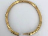 a close up of a gold bracelet on a white surface