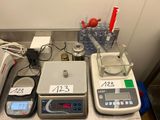 trois balances électroniques posées sur un comptoir, avec une échelle de mesure