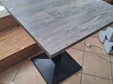 a wooden table with a metal base on a tiled floor