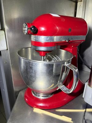 a red mixer sitting on a counter in a kitchen