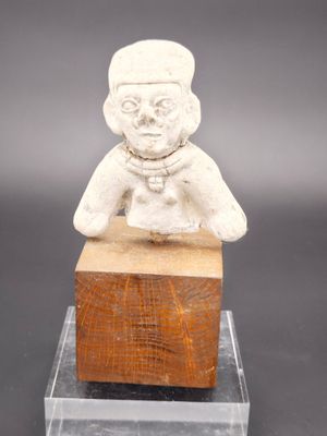 une image représentant une petite statue d'une personne assise sur un bloc de bois