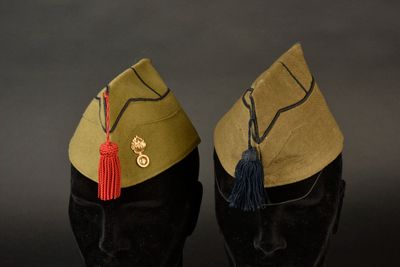 une paire de casquettes militaires ornées de pompons, posées l'une sur l'autre