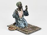 figurine représentant un homme assis sur un tapis, sur fond blanc
