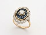 a close up of a diamond and sapphire ring on a white surface