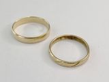 two gold wedding rings sitting on a white surface