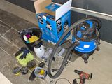 une boîte bleue contenant un aspirateur et d'autres outils, posée par terre