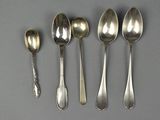 six spoons and a spoon rest on a gray surface