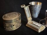 un récipient en argent et une coupe en argent posés sur une table noire