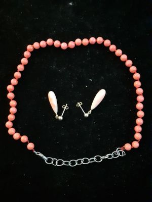 a close up of a necklace and earrings on a black surface