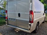 the back of a silver van parked in a gravel lot