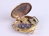 a gold pocket watch with gears inside of it on a white surface