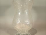 un petit vase en verre posé sur une surface blanche