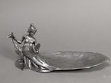 une statue représentant une femme assise sur un bol en forme de feuille