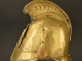 an antique gold helmet with a metal base on a black background