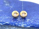 une paire de boucles d'oreilles en or et diamants posée sur une pierre bleue