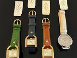 four different colored watches are lined up on a black surface