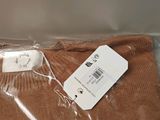 a brown sweater with a tag on it sitting on a plastic bag