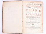 an open book on a white surface with red writing on it