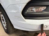 a person holding a remote control in front of a white car