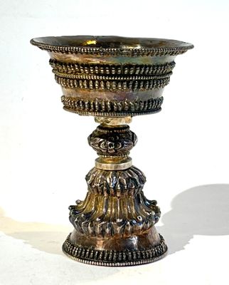 une coupe en argent posée sur un socle, sur fond blanc