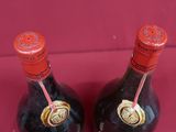 two bottles of wine sitting on top of a red table