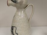 a white vase with a dog on it on a table