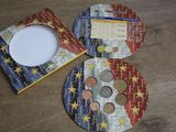 three coasters with coins on them sitting on a table