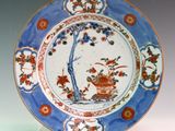 a blue and white plate with a tree and flowers on it
